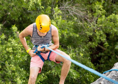 man in harness rappelling down face of rock
