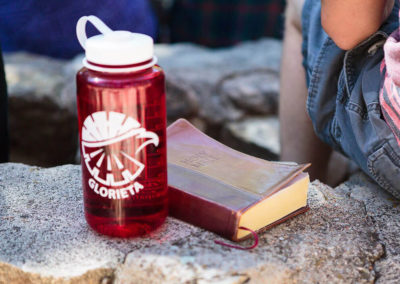 bible and water bottle sitting on rock next to boy camper