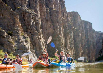 group of young adults in inflatable kayaks row down river at Big Bend