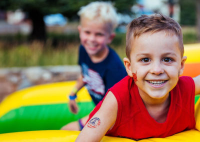 young city camp camper boy smiling after coming down inflatable slide