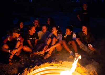 girl campers gathered around a campfire