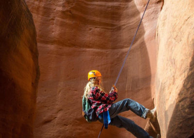 girl in harness repelling down canyon wall