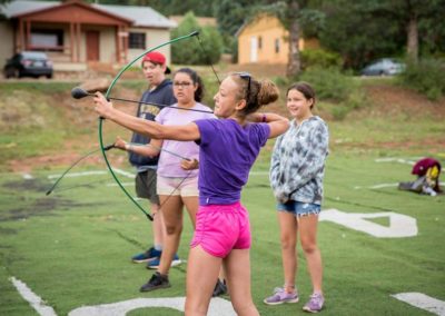 day camp girl pulls back on bow to test out archery skills