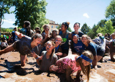 students in mud pit trying to take a group picture