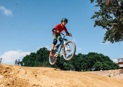 day camp boy on mountain bike comes over jump on bmx track