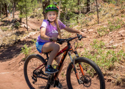 young girl in helmet riding a mountain bike down the trail