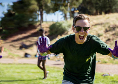 summer staff counselor running across field with purple paint all over hands
