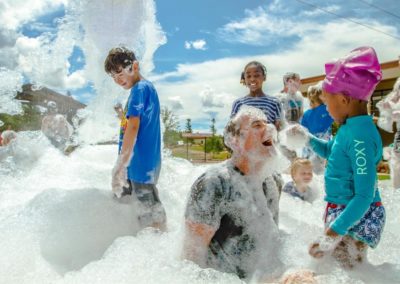young girl puts foam all over her dad's face during family camp foam party