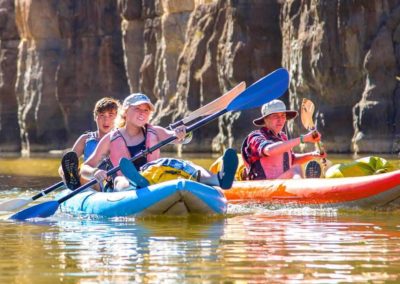 pairs of high school students paddle down river on inflatable canoes