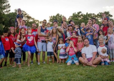 large family dressed up for fourth of july makes silly faces at the camera