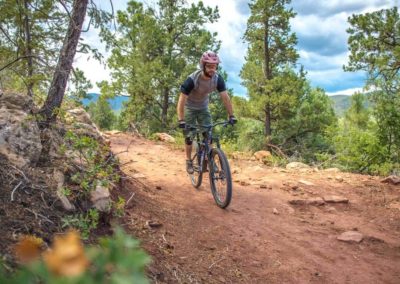 man mountain biking down smooth dirt trail