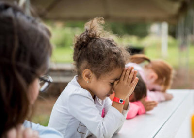young camper holds hands together to pray