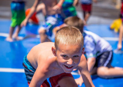 city camp boy campers sliding on inflatable blue jumping mat