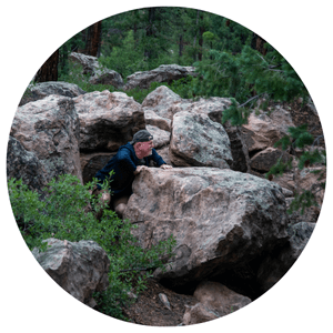 older man playing hide and seek among natural bolders