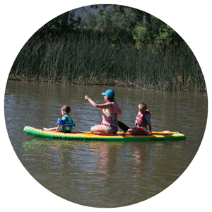 mom and 2 kids paddling in the water on a paddleboard